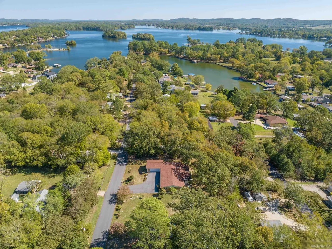 Aerial view of 186 Echo Point, a single-level home among the trees with Lake Hamilton beyond